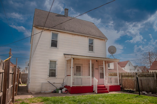 back of house with covered porch and a shingled roof