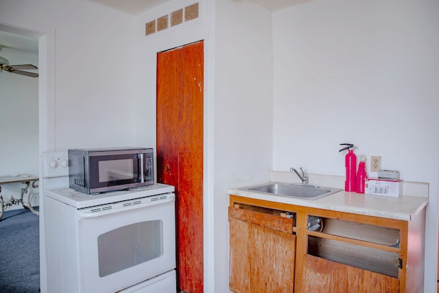 kitchen featuring stainless steel microwave, a sink, white electric range oven, a ceiling fan, and light countertops