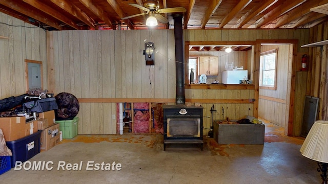 940 Wood River Rd, Grayling, MI 49738 - living room featuring a ceiling fan, a wood stove, electric panel, and unfinished concrete flooring