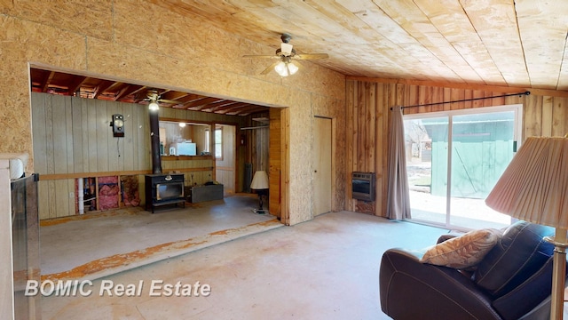 940 Wood River Rd, Grayling, MI 49738 - living area featuring a wood stove, a ceiling fan, lofted ceiling, wooden walls, and heating unit