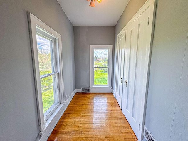 doorway with light wood-style floors, healthy amount of natural light, and baseboards