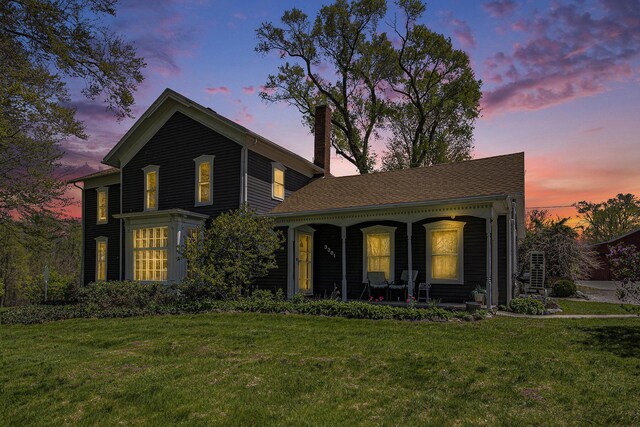 view of front facade featuring a porch, a front lawn, and a chimney