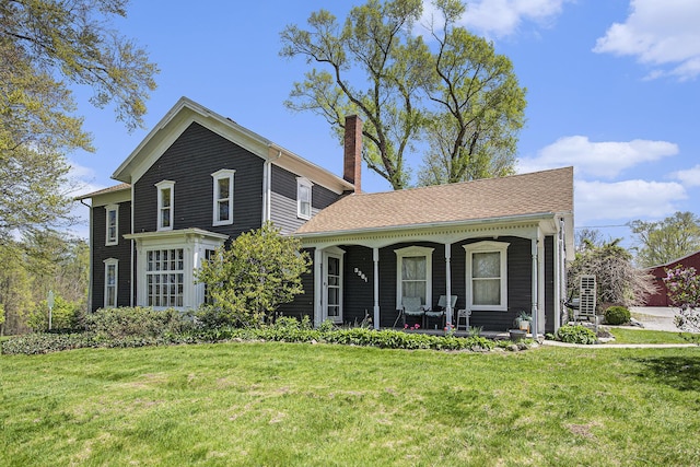 view of front of property with covered porch, a front lawn, and a chimney