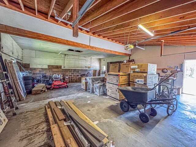 misc room featuring unfinished concrete flooring and concrete block wall