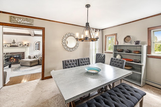 carpeted dining space with a chandelier, crown molding, a brick fireplace, baseboards, and a baseboard heating unit