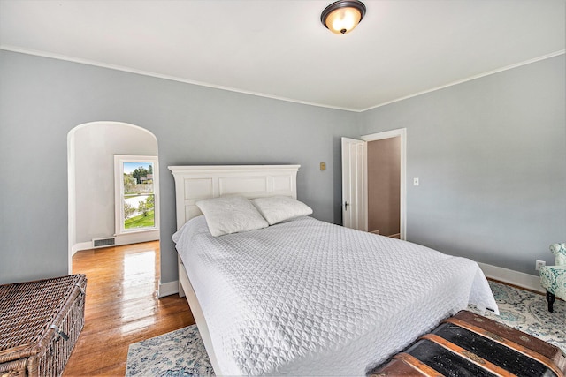 bedroom with wood finished floors, crown molding, and baseboards