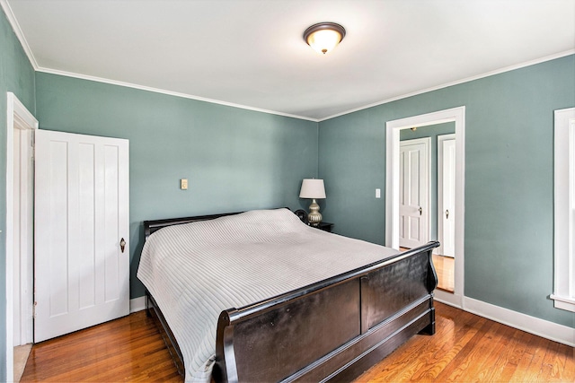 bedroom with wood finished floors, baseboards, and ornamental molding