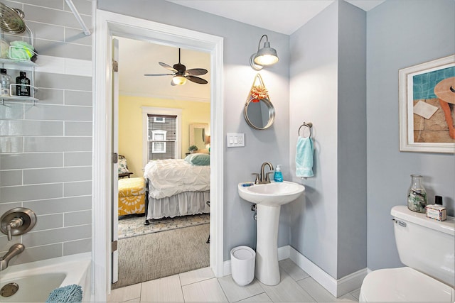 ensuite bathroom featuring toilet, ceiling fan, baseboards, shower / bathtub combination, and a sink