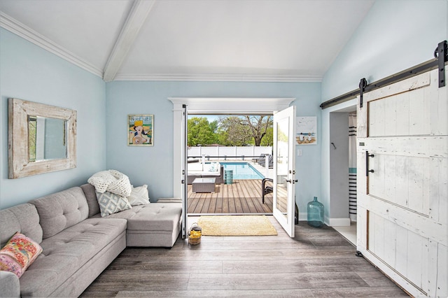living area with a barn door, wood finished floors, ornamental molding, and baseboards
