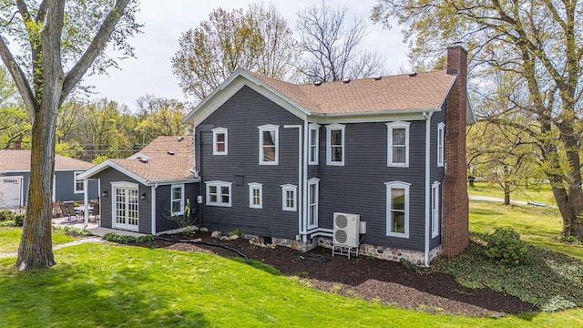 rear view of house with a chimney, a lawn, and a cooling unit
