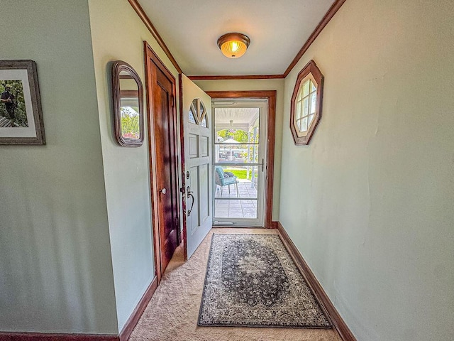 doorway to outside featuring carpet, crown molding, and baseboards