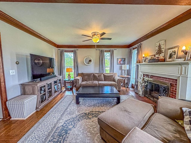 living area with ornamental molding, wood finished floors, a fireplace, a ceiling fan, and baseboards
