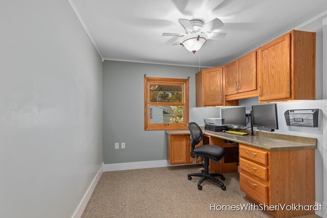 office space featuring light colored carpet, a ceiling fan, baseboards, and crown molding
