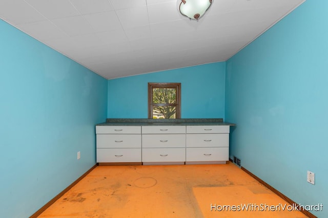 unfurnished bedroom with baseboards, vaulted ceiling, and concrete floors