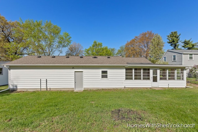 back of property featuring a sunroom, a lawn, and a shingled roof