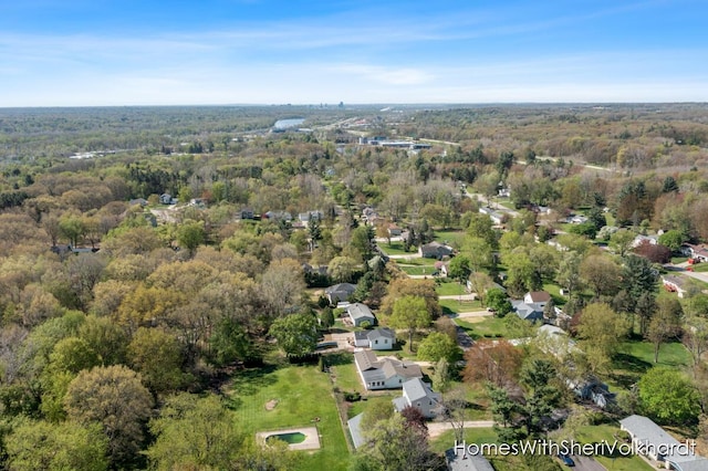 aerial view of property and surrounding area with a forest and nearby suburban area