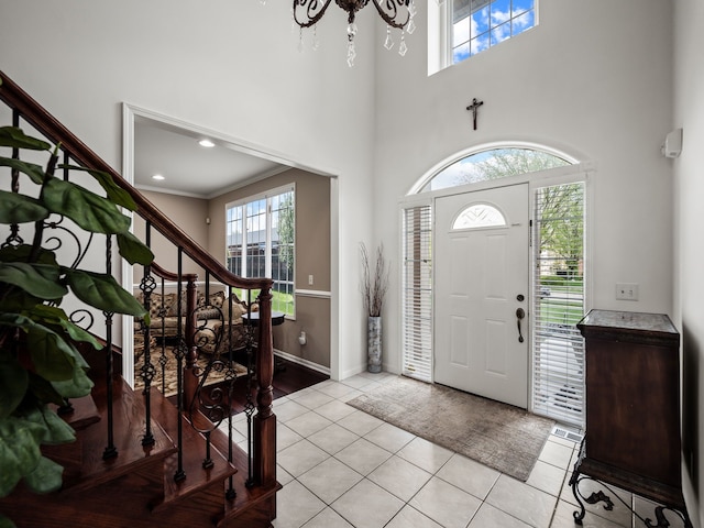 entryway with stairs, light tile patterned flooring, a towering ceiling, and baseboards