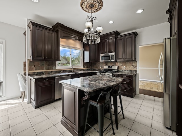 kitchen featuring stainless steel appliances, a chandelier, light tile patterned flooring, dark brown cabinets, and backsplash