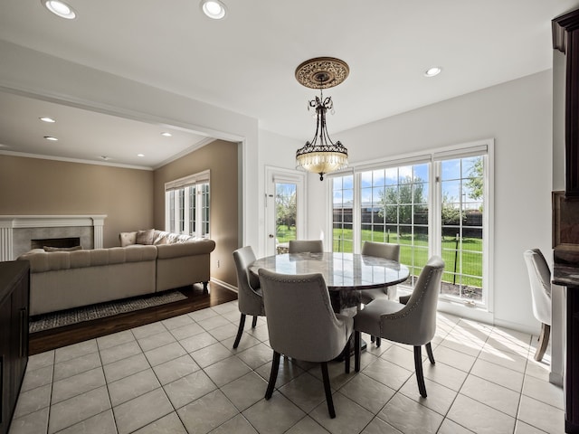 dining room featuring healthy amount of natural light, light tile patterned floors, ornamental molding, recessed lighting, and a tiled fireplace