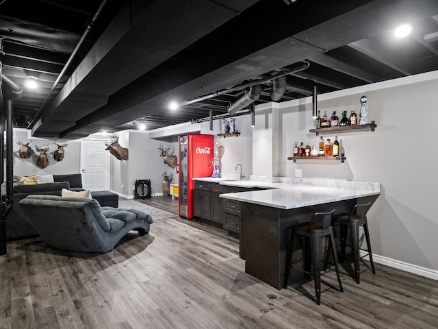 indoor wet bar with wood finished floors and baseboards