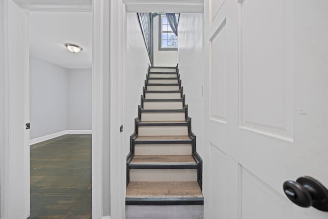 staircase featuring baseboards and wood finished floors