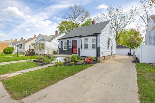 bungalow with a detached garage, an outbuilding, a shingled roof, and a chimney