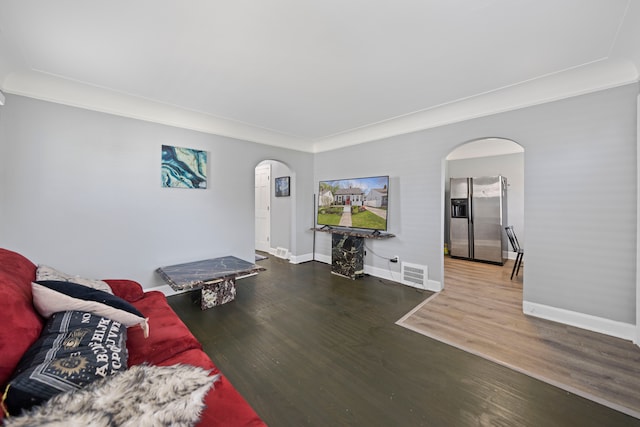 living area featuring arched walkways, wood finished floors, and baseboards