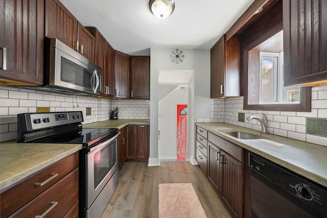 kitchen with appliances with stainless steel finishes, light wood-style flooring, a sink, and light countertops