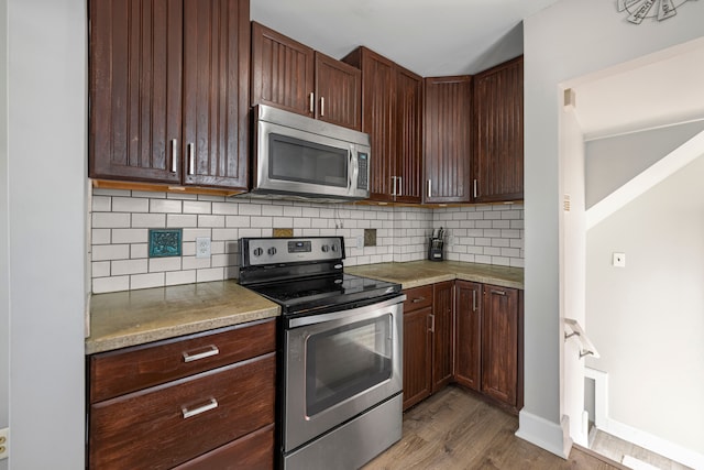 kitchen featuring appliances with stainless steel finishes, wood finished floors, decorative backsplash, and light countertops