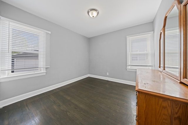 empty room with baseboards and dark wood-type flooring
