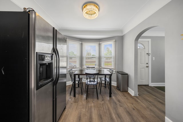 dining room with arched walkways, wood finished floors, and baseboards
