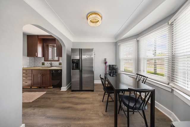dining space with arched walkways, baseboards, dark wood-style flooring, and healthy amount of natural light