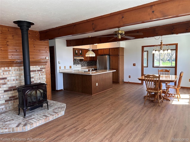 2800 E Booth Rd, Au Gres, MI 48703 - kitchen with freestanding refrigerator, under cabinet range hood, a wood stove, wood finished floors, and a peninsula