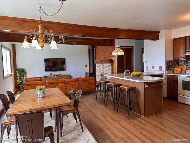2800 E Booth Rd, Au Gres, MI 48703 - dining room with light wood-style floors, a wood stove, a chandelier, beam ceiling, and ceiling fan