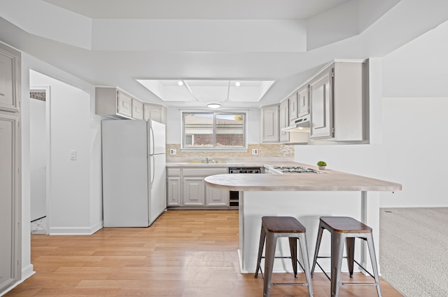 13488 Kingsville Dr, Sterling Heights, MI 48312 - kitchen featuring freestanding refrigerator, a peninsula, stainless steel gas stovetop, dishwasher, and a tray ceiling