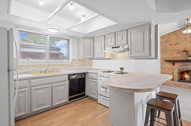 13488 Kingsville Dr, Sterling Heights, MI 48312 - kitchen with white appliances, a sink, under cabinet range hood, light wood-style floors, and a breakfast bar area