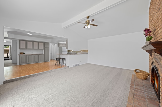 13488 Kingsville Dr, Sterling Heights, MI 48312 - unfurnished living room with ceiling fan, a fireplace, beam ceiling, light carpet, and high vaulted ceiling