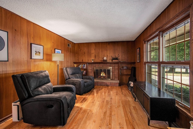 2021 Skyler Dr, Kalamazoo, MI 49008 - living room featuring plenty of natural light, wood walls, a textured ceiling, a fireplace, and light wood-type flooring