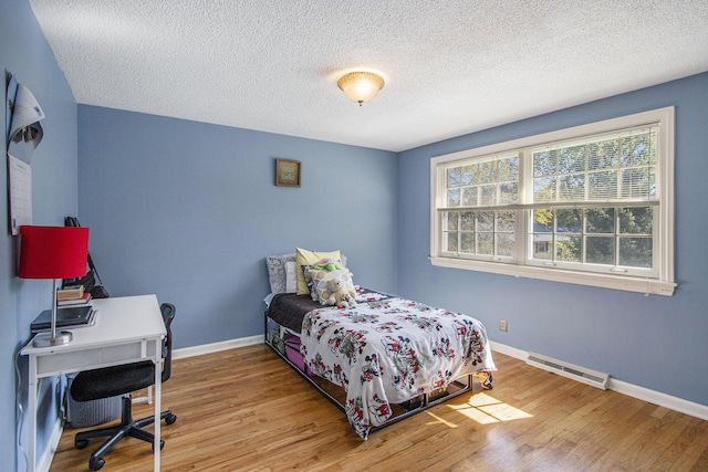 2021 Skyler Dr, Kalamazoo, MI 49008 - bedroom with wood finished floors, a textured ceiling, baseboards, a baseboard radiator, and an office area