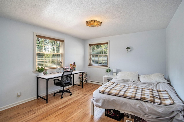 2021 Skyler Dr, Kalamazoo, MI 49008 - bedroom with light wood-type flooring, a textured ceiling, a desk, baseboards, and a baseboard radiator