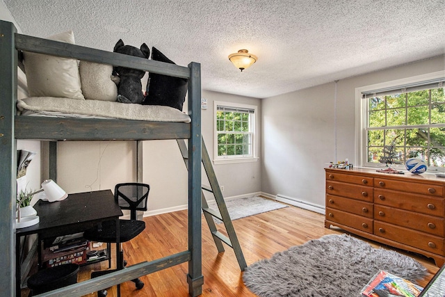 2021 Skyler Dr, Kalamazoo, MI 49008 - bedroom with wood finished floors, baseboard heating, a textured ceiling, and baseboards