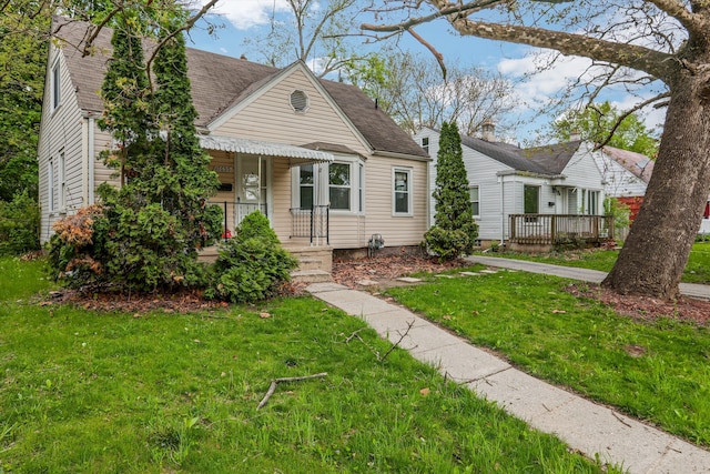 view of front of house featuring covered porch, a front yard, and roof with shingles