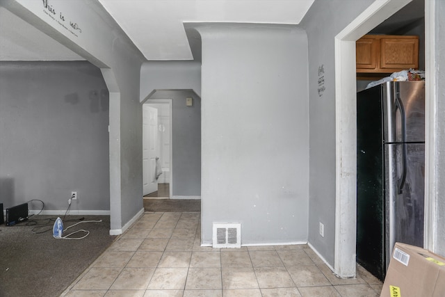 unfurnished room with light tile patterned flooring, arched walkways, and baseboards