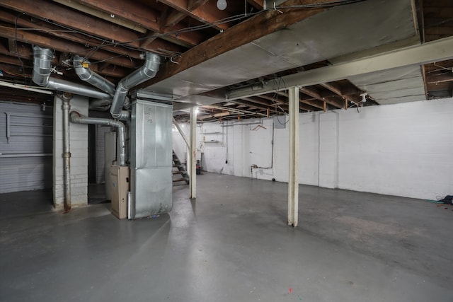 unfinished below grade area featuring heating unit and stairs