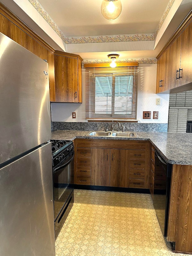 kitchen featuring black appliances, a sink, light flooring, and brown cabinets