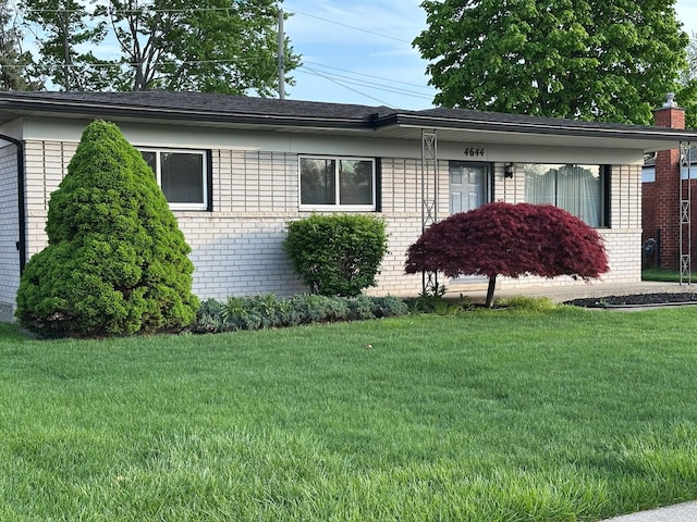 view of front of house featuring brick siding, a front lawn, and a chimney