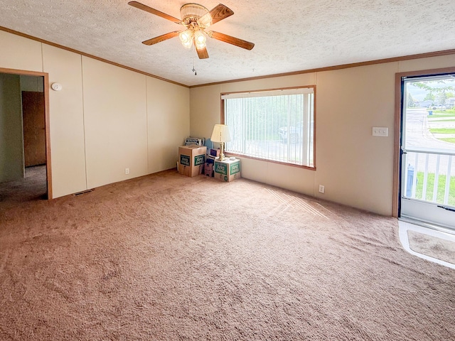 carpeted spare room with crown molding, a ceiling fan, plenty of natural light, and a textured ceiling