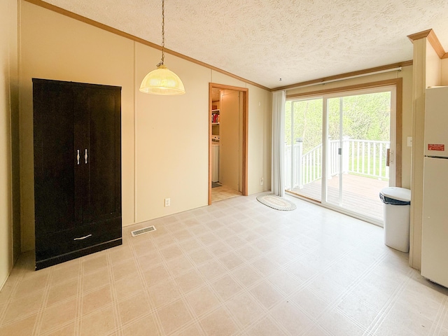 empty room with crown molding, lofted ceiling, tile patterned floors, and a textured ceiling