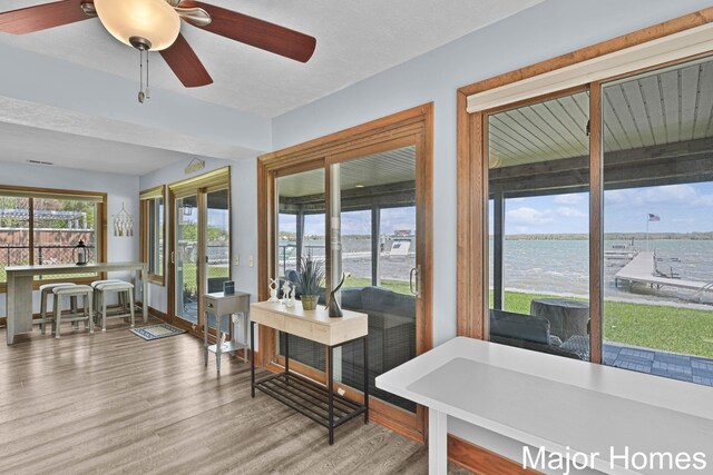 sunroom with wood finished floors and a water view