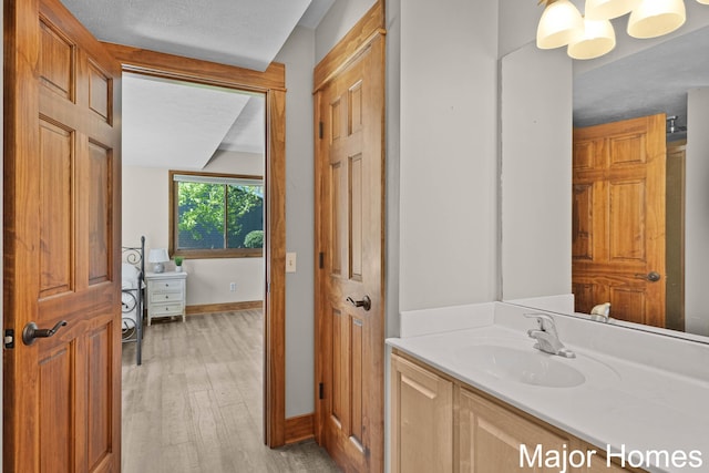 bathroom featuring wood finished floors, baseboards, and vanity